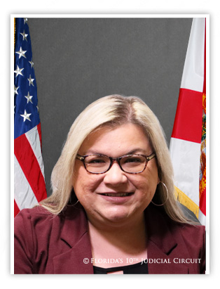 Portrait of Hearing Officer Kymberly Clements with American Flag in the background on her right, and the State of Florida flag in the background on her left.