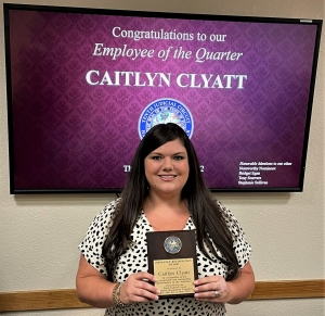 Caitlyn Clyatt holding Employee of the Quarter award plaque