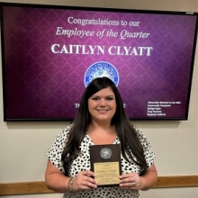 Caitlyn Clyatt holding Employee of the Quarter award plaque